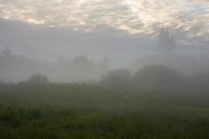 foggy summer morning landscape with the church on the hill in the background photo