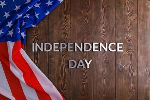 the words independence day laid on brown wooden planks surface with crumpled united states of america flag photo