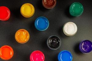 full-frame close-up view d of opened small gouache paint jars on black surface photo