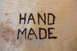 the word hand made handwritten on flat wooden background with electrical woodburner photo