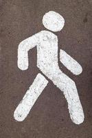 Señal de calle blanca para caminar en la carretera de asfalto de la ciudad gris foto