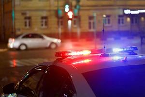 night police car lights in city street with civilian car in blurry background photo