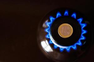 quemador de estufa de gas con una moneda de euro encima, quemando gas natural con llama azul foto