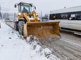 tula, rusia 21 de noviembre de 2020 tractor con gran pala limpiando nieve en la carretera a la luz del día de invierno. foto