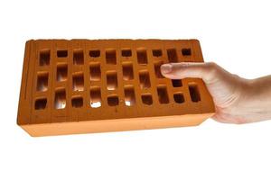 bare caucasian hand holding orange perforated clay brick - isolated photo