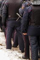 tula, rusia 23 de enero de 2021 multitud de policías en uniforme negro con chalecos antibalas y pistolas - vista desde atrás. foto