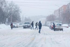 tula, rusia 13 de febrero de 2020 ciudadanos cruzando la carretera de la ciudad durante la fuerte caída de nieve. foto