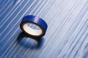 one roll of old blue pvc duct tape on ti's self flat background photo