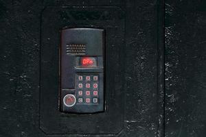 An intercom on old black painted steel surface with a keypad, digital display and rfid sensor for calling close-up photo