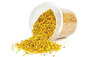 bee pollen granules in small plastic container isolated on white background photo