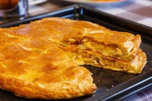 freshly baked domestic ossetian pie on a baking sheet with cutted piece over photo