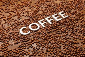 word coffee laid with silver letters on wooden surface covered with coffee beans photo