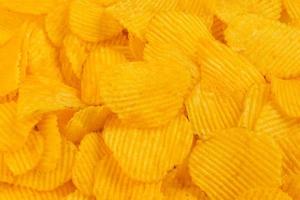 close-up full frame yellow wavy potato chips heap background photo