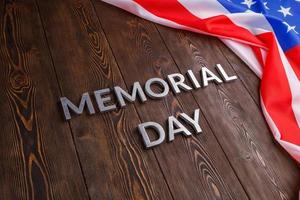 the words memorial day laid with silver metal letters on wooden board surface with crumpled usa flag photo