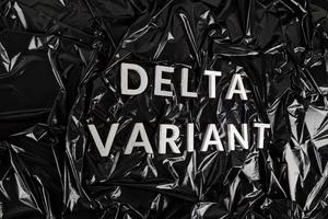 words delta variant laid with silver metal letters on crumpled black plastic bag background in diagonal perspective photo