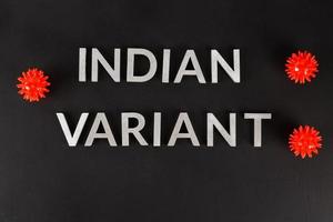 words indian variant laid with silver metal letters on flat matte black surface with small virus models photo