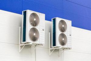 two double condensing units of air conditioner on blue and white metal wall photo