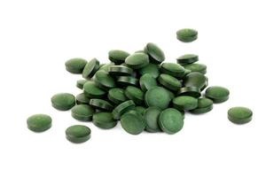 a small pile of green spirulina pills isolated on white background photo