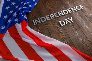 las palabras día de la independencia colocadas en la superficie de tablones de madera marrón con la bandera de los estados unidos de américa arrugada foto