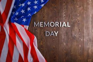 the words memorial day laid with silver metal letters on wooden board surface with crumpled usa flag photo