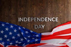 the words independence day laid on brown wooden planks surface with crumpled united states of america flag photo