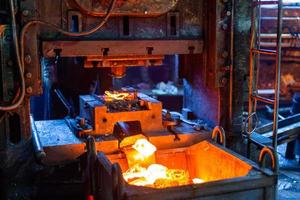 imagen de primer plano de piezas de trabajo de acero caliente forjadas frescas después de la formación de la prensa en una fábrica sucia y oscura foto