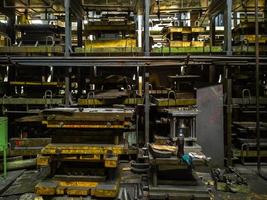 messy stamping shop with large stamps rack inside metalworking factory photo