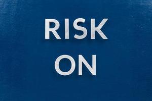 the words risk on laid with silver metal letters on classic blue surface for stock market background photo