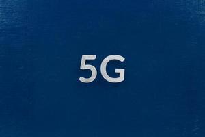 the word 5G laid with aluminium letters on dark blue background photo
