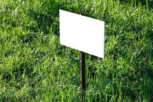 blank white sign mockup on green lawn background - close-up with selective focus photo