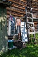 the clothes are dried on a rope behind old wooden house at summer photo