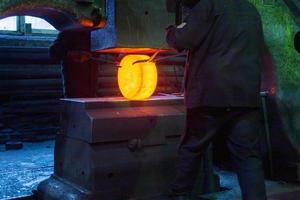 close-up picture of hot steel free forging process with big mechanical hammer machine photo