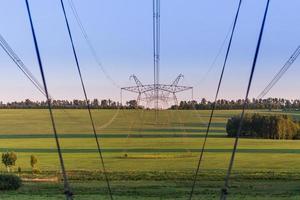 huge power line towers on field at summer evening photo