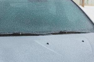 frost covered white car bonnet, wipers and windshield - close-up background with selective focus photo