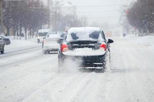 los pedazos de nieve en la carretera fluyen de las ruedas de un camión sucio que se mueve rápido en la ciudad a la luz del día con un enfoque selectivo. foto