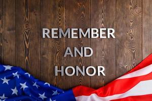 words remember and honor laid with silver metal letters on wooden background with USA flag underneath photo