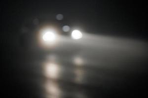 defocused photo of blurred car moving on empty night foggy road