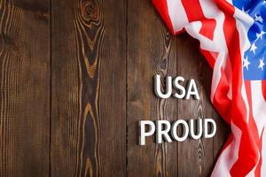 words USA proud laid with silver metal letters on brown wooden surface with flag of United States of America photo