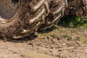 dirty double wheels of agriculture tractor on dirt road at sunny summer day photo