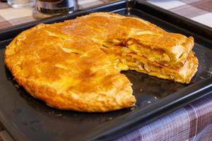 freshly baked domestic ossetian pie on a baking sheet with cutted piece over photo