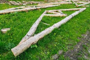 forged steel stripe connection of wooden log beams for roof support girder framework laid on green grass at summer day photo