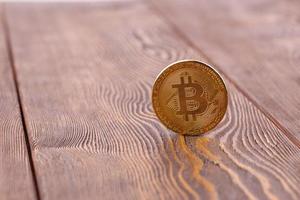 bitcoin coin standing on wooden background - close-up with selective focus photo