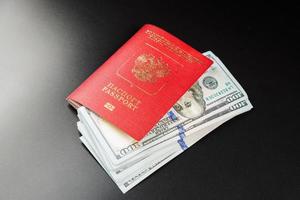russian international passport with inserted US dollars on black background photo