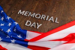 the words memorial day laid with silver metal letters on wooden board surface with crumpled usa flag photo