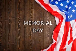 the words memorial day laid with silver metal letters on wooden board surface with crumpled usa flag photo