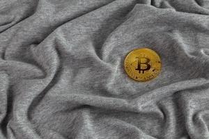 brillador de bitcoin dorado sobre tela de algodón gris arrugado foto