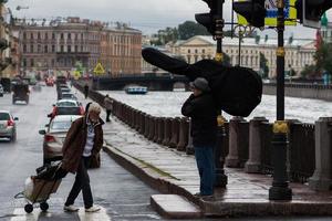 san petersburgo, rusia, 22 de julio de 2015, anciano sin hogar con carro y músico con estuche de instrumentos musicales. foto