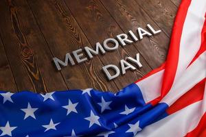 the words memorial day laid with silver metal letters on wooden board surface with crumpled usa flag photo