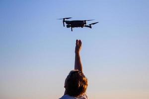 hombre caucásico rubio atrapando un pequeño dron quadcopter foto