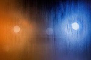 an abstract background of foggy wet window glass at night with blurry street lights photo
